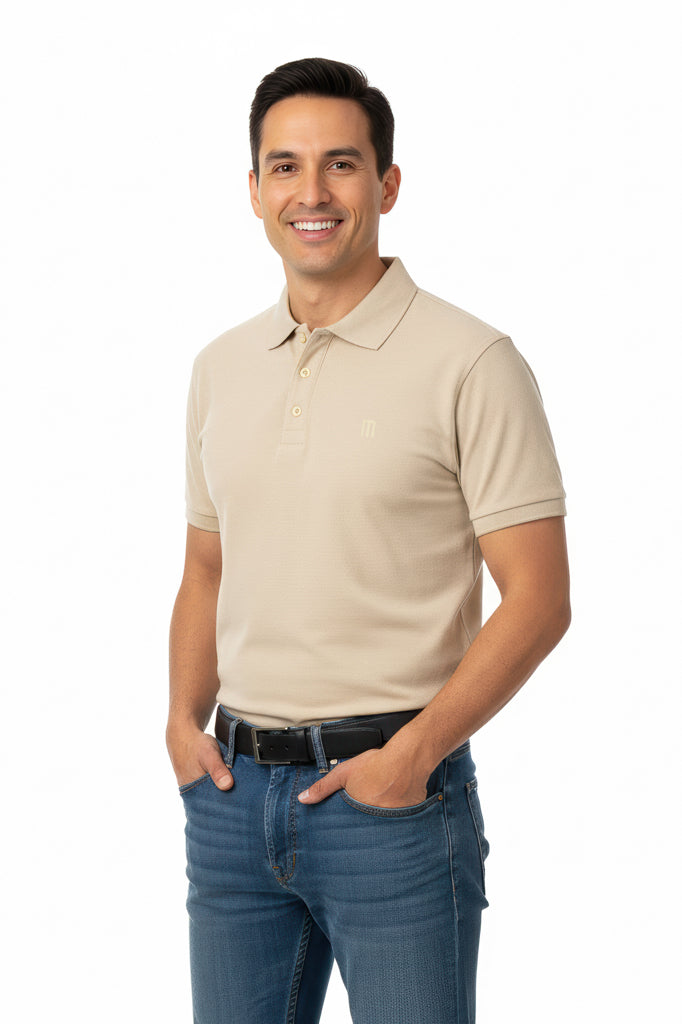 Smiling man with short dark hair wearing a beige polo shirt, a black belt, and blue jeans, with his hands in his pockets.