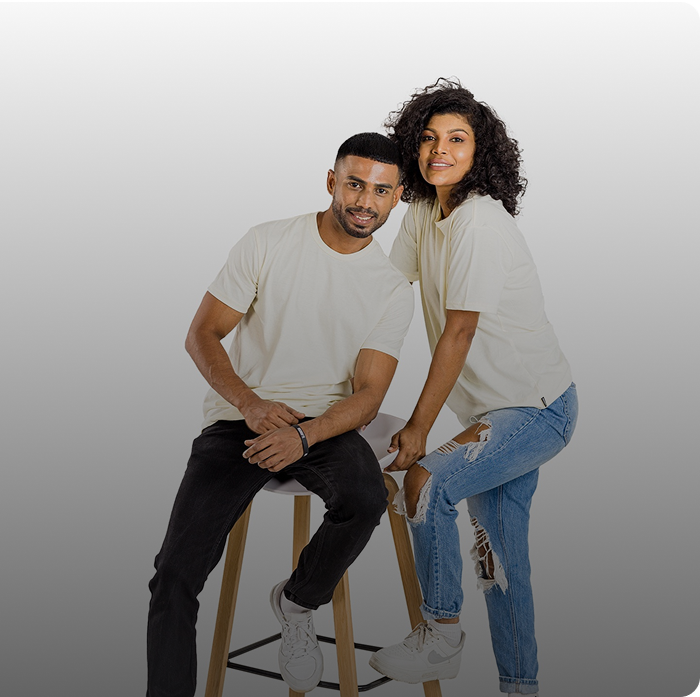 Man and a woman are standing next to a stool, both wearing plain light-colored t-shirts and jeans.