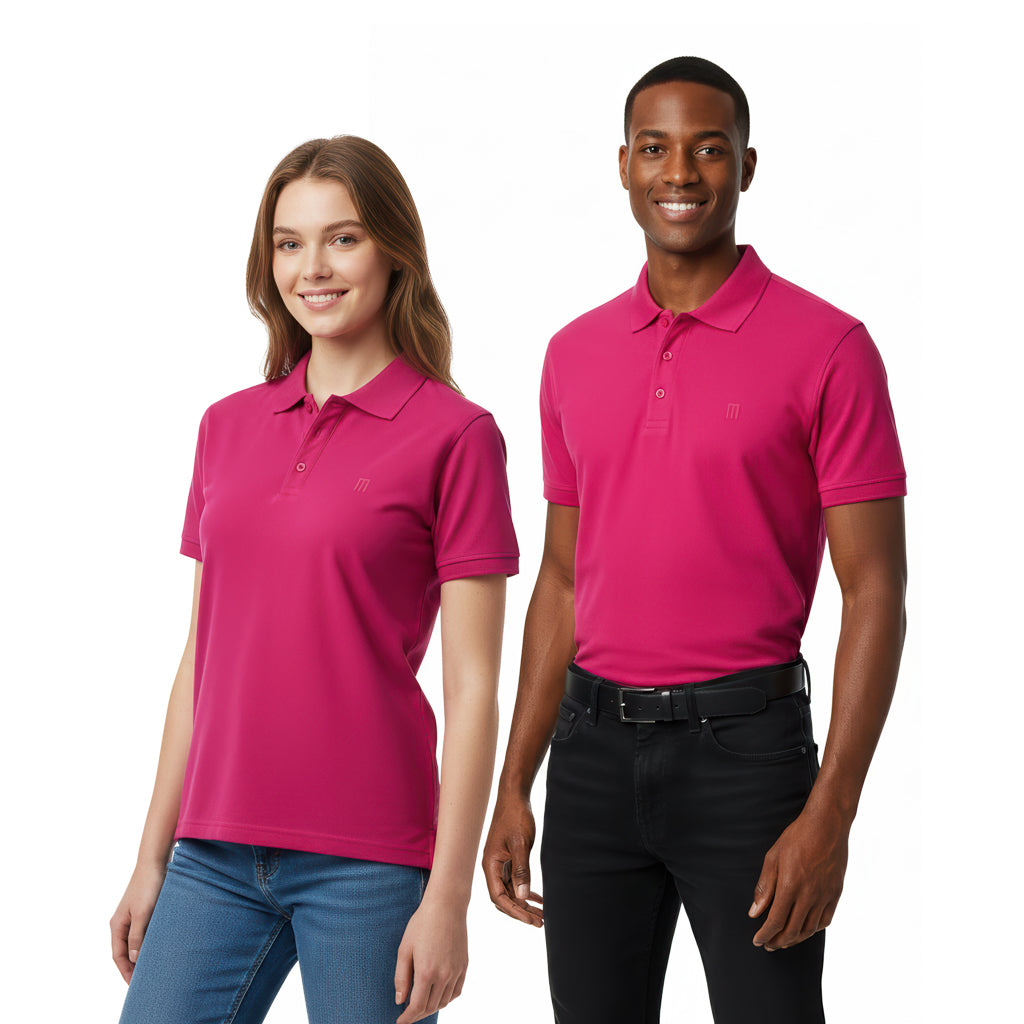smiling man and woman wearing matching pink polo shirts. The woman is wearing blue jeans and the man is wearing black jeans with a black belt.