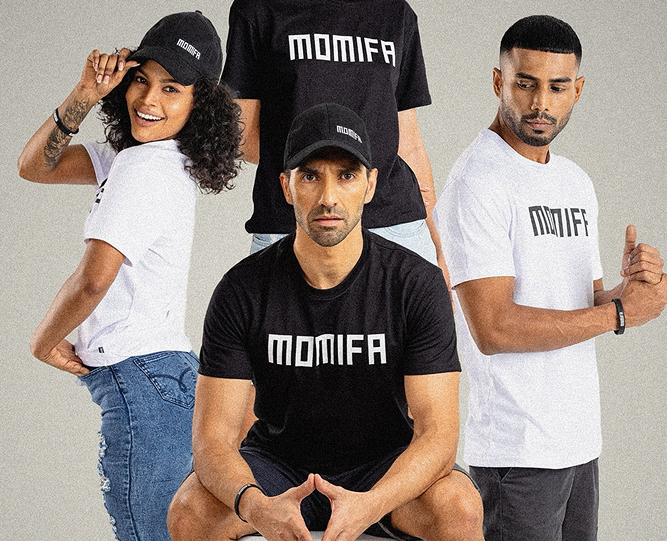 Four people wearing black and white t-shirts and hats with the brand name "MOMIFA" printed on them, posing together in a studio.