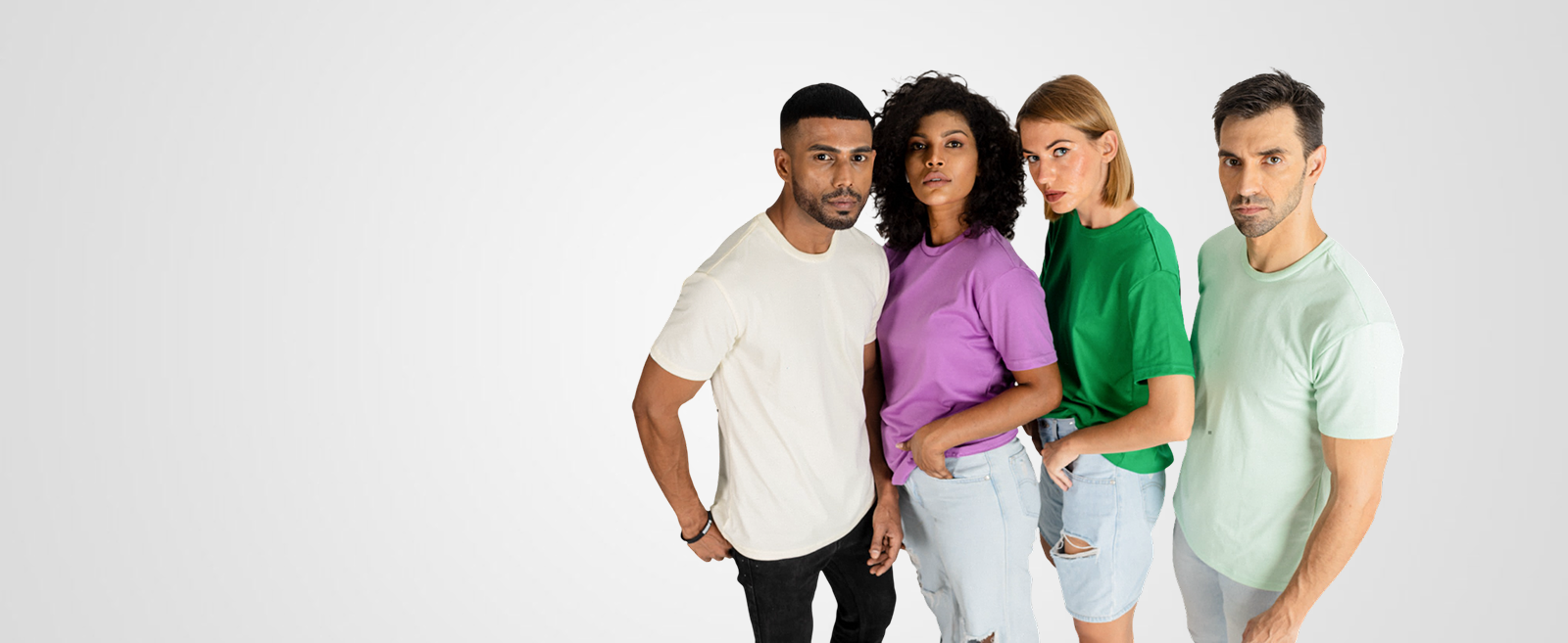 Four people, two men and two women, are standing together. They are wearing plain, solid-colored t-shirts in off-white, purple, green, and mint green.