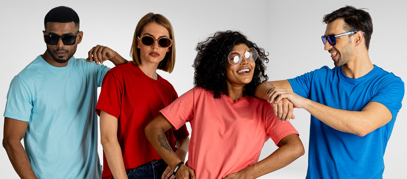 Four people, two men and two women, are posing together. They are all wearing solid-colored t-shirts in light blue, red, pink, and royal blue, along with various sunglasses.