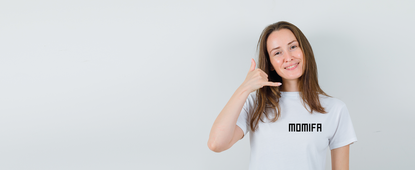 Smiling woman with long brown hair wears a white t-shirt, making a "call me" gesture.Smiling woman with long brown hair wears a white t-shirt, making a "call me" gesture.