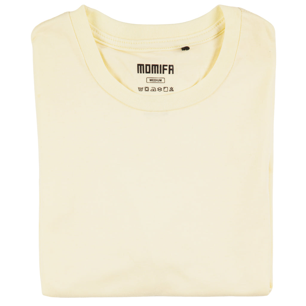Neatly folded cream-colored t-shirt with a "MOMIFA" brand tag is displayed against a black background.