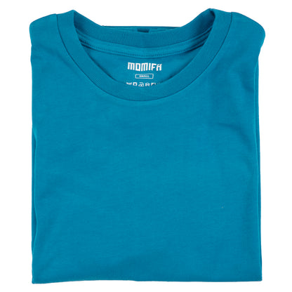 Folded teal blue t-shirt with the white "MOMIFA" and "SMALL" brand tag visible at the collar area.