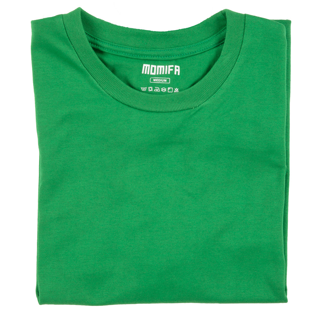 Green t-shirt with a white label in the neck. The label shows the brand "MOMIFA", size "MEDIUM", and laundry symbols.