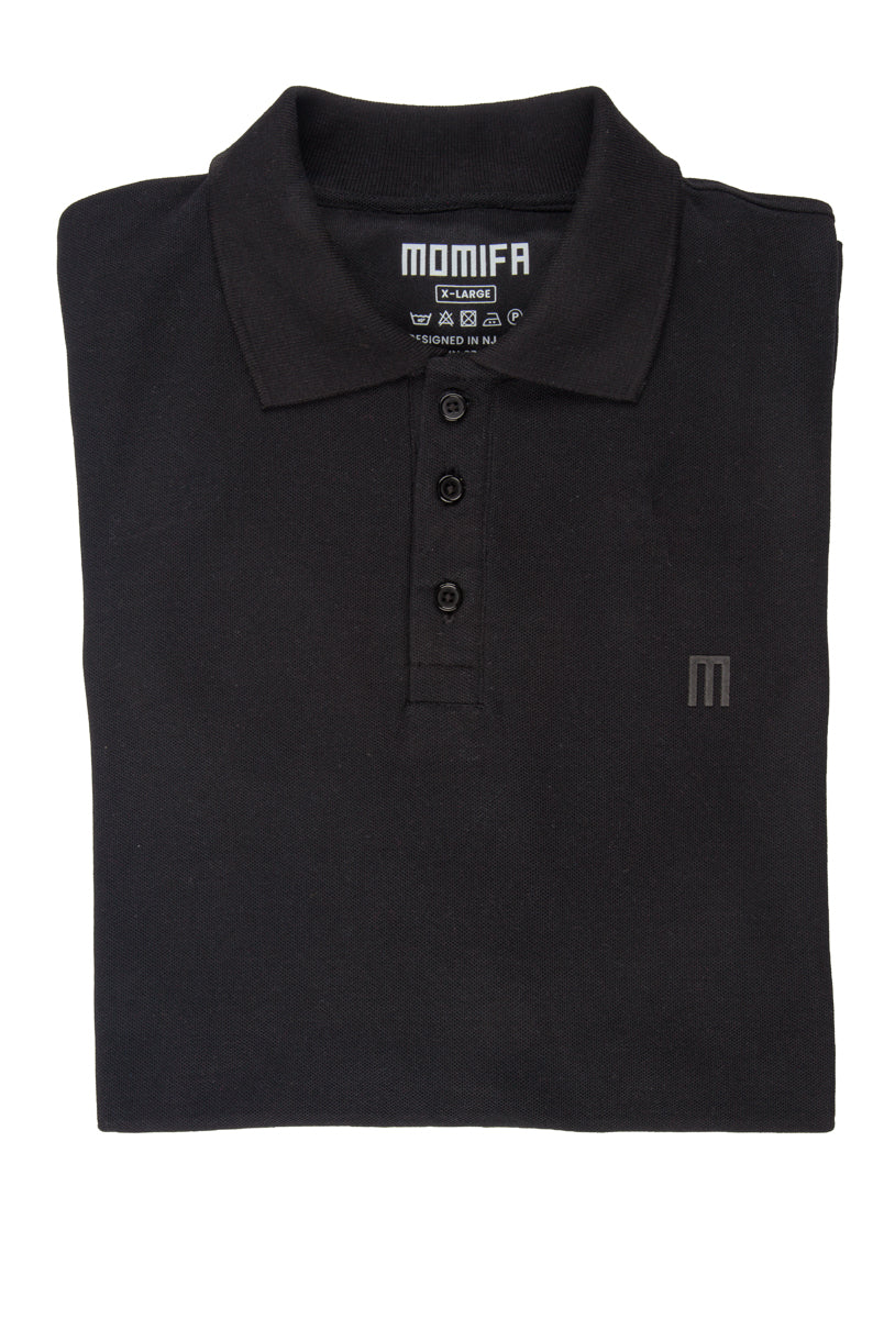 black polo shirt with a collar, a three-button placket, and a subtle ""M"" logo on the left chest, with a tag on the collar.