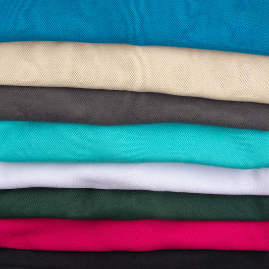 Folded solid-colored fabric pieces, including blue, beige, grey, turquoise, white, green, pink, and black.